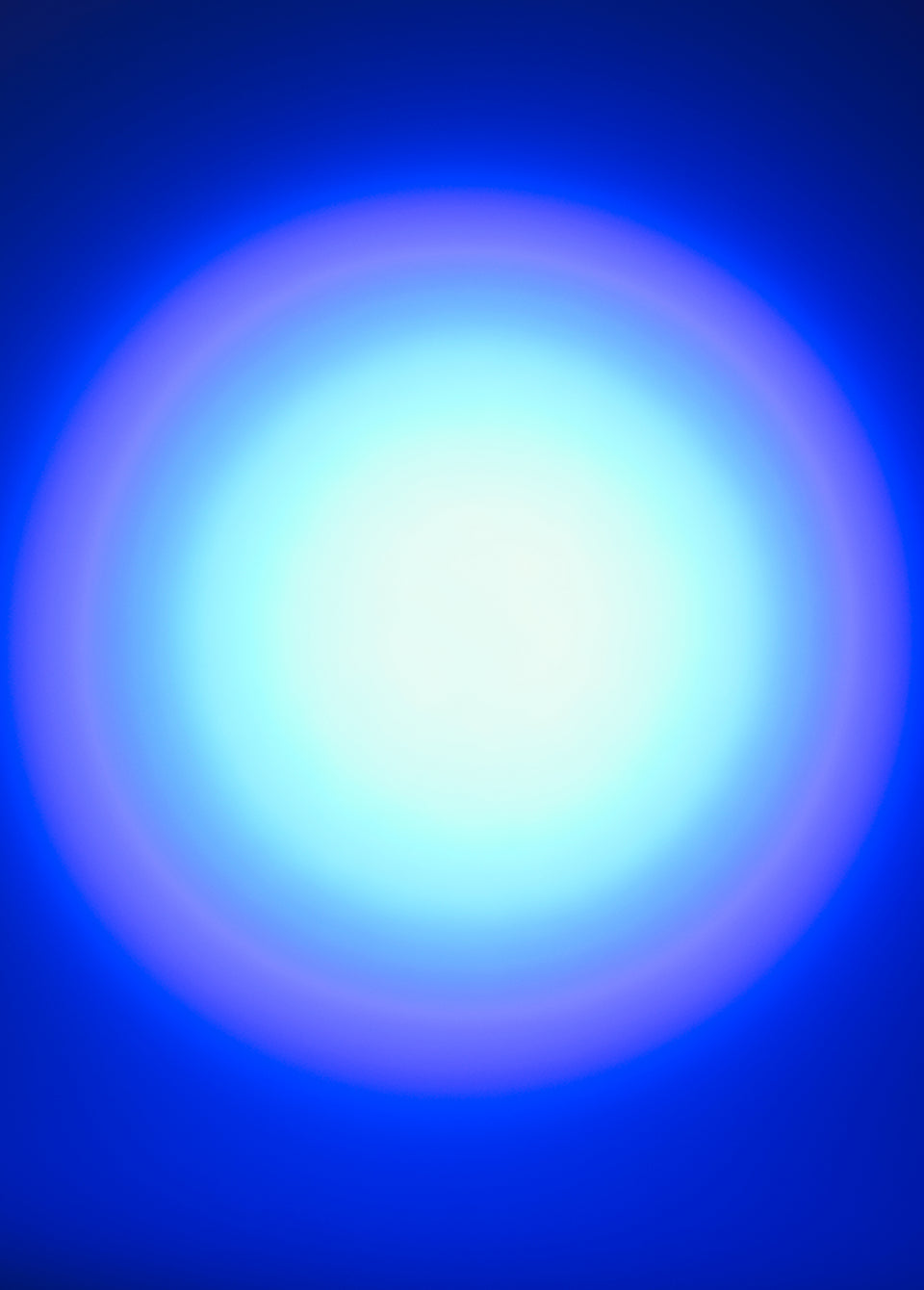 A circular gradient light effect with a bright white center fading to light blue and purple, set against a deep blue background.