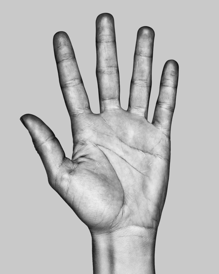 A black and white photograph of a human hand with all five fingers extended, shown against a solid light gray background.
