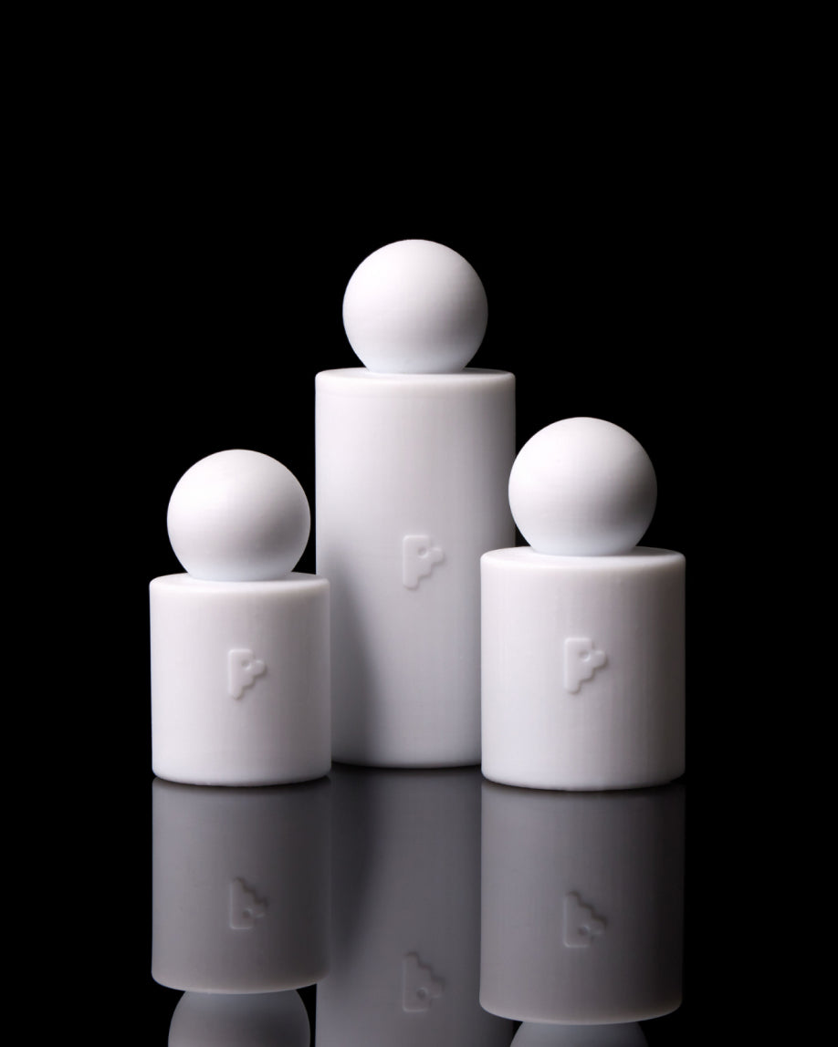 Three white cylindrical containers with spherical tops, arranged in a pyramid on a reflective black surface. Each container features a small embossed logo.