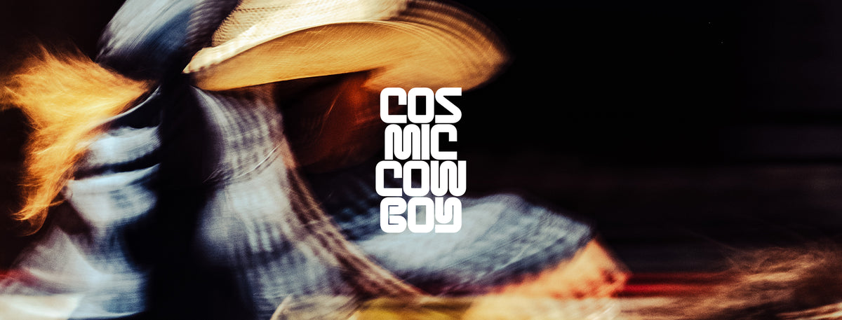 A stylized, motion-blurred portrait of a person wearing a cowboy hat and denim clothing, with the text 'COSMIC COWBOY' overlaid vertically in white on the right side against a dark background.