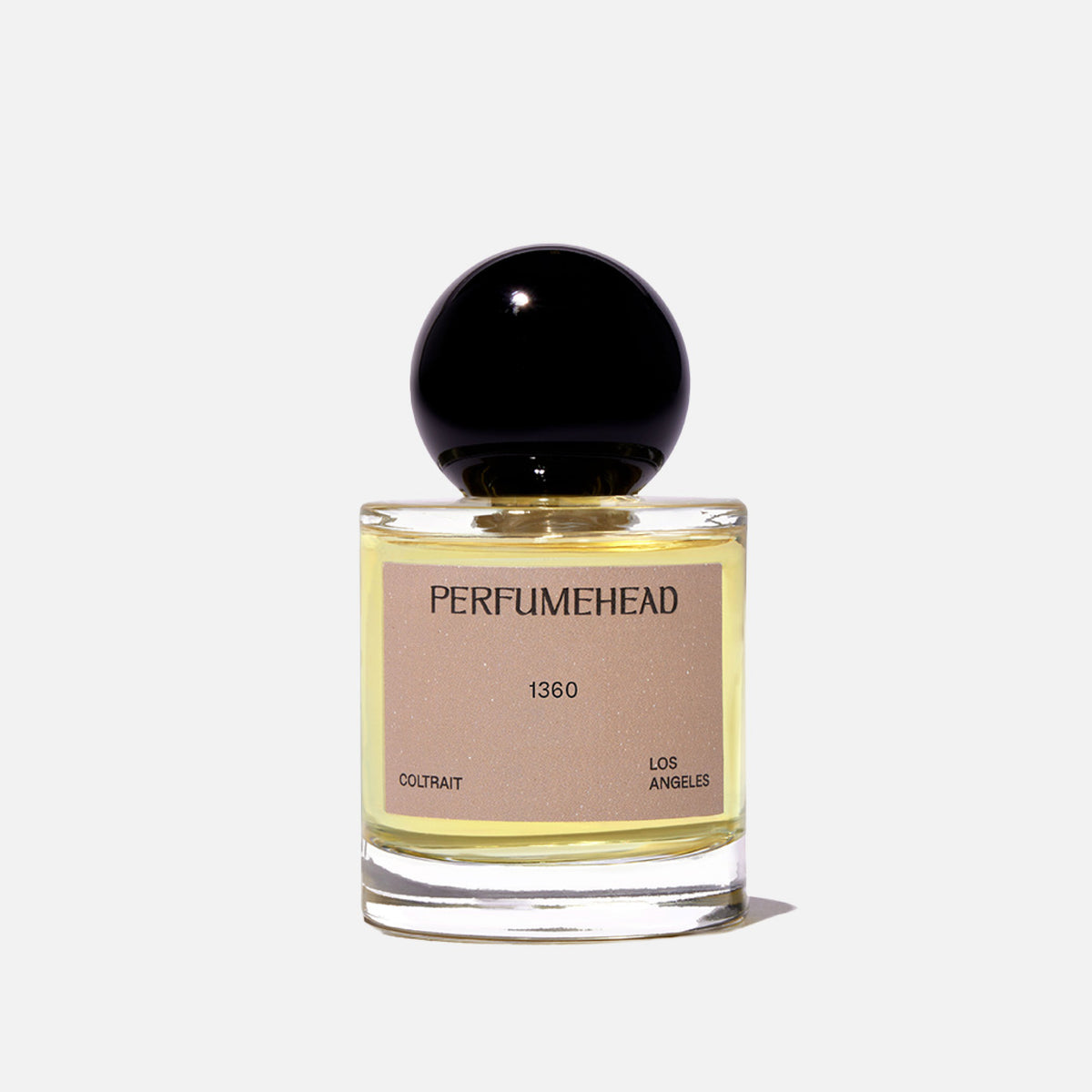 A bottle of Perfumehead 1360 coltrait on a white background. The bottle is clear glass showing a pale yellow liquid inside, with a beige label and a glossy black spherical cap.
