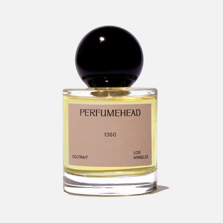 A bottle of Perfumehead 1360 Coltrait with a black spherical cap and a beige label, set against a white background.