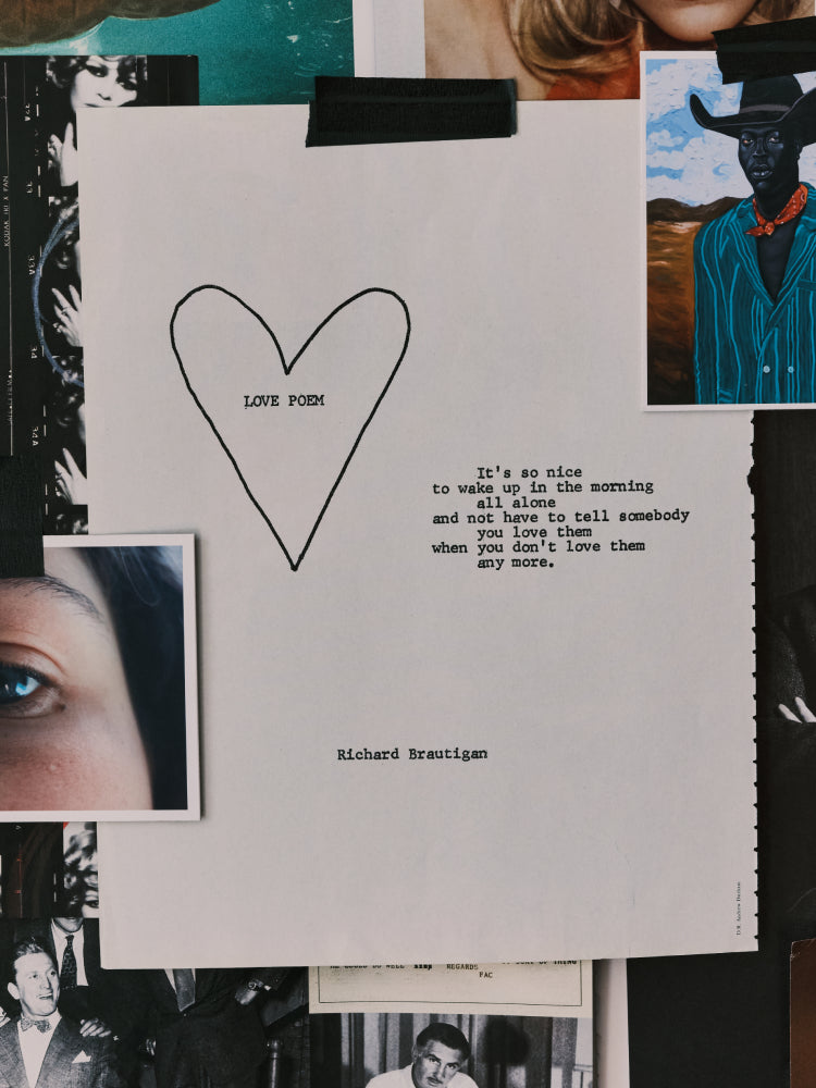 A typewriter-style letter print on white paper with a hand-drawn heart and the text 'LOVE YOU' and a quote attributed to Richard Brautigan. The print is photographed among other papers, photos, and clips.