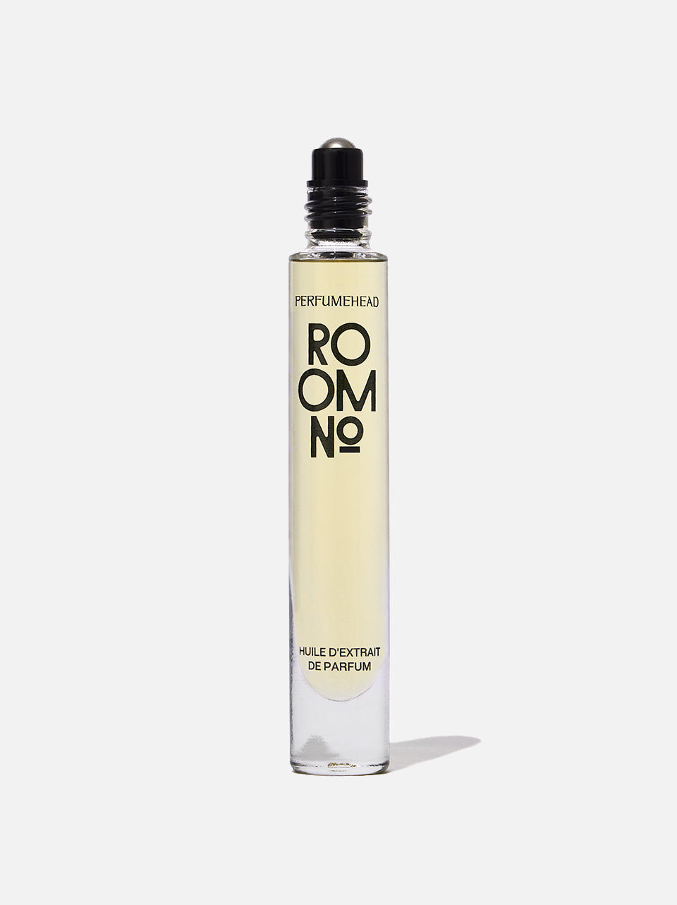A clear glass rollerball perfume bottle with pale yellow liquid inside, featuring a black cap and a label with bold black text reading 'ROOM NO.'