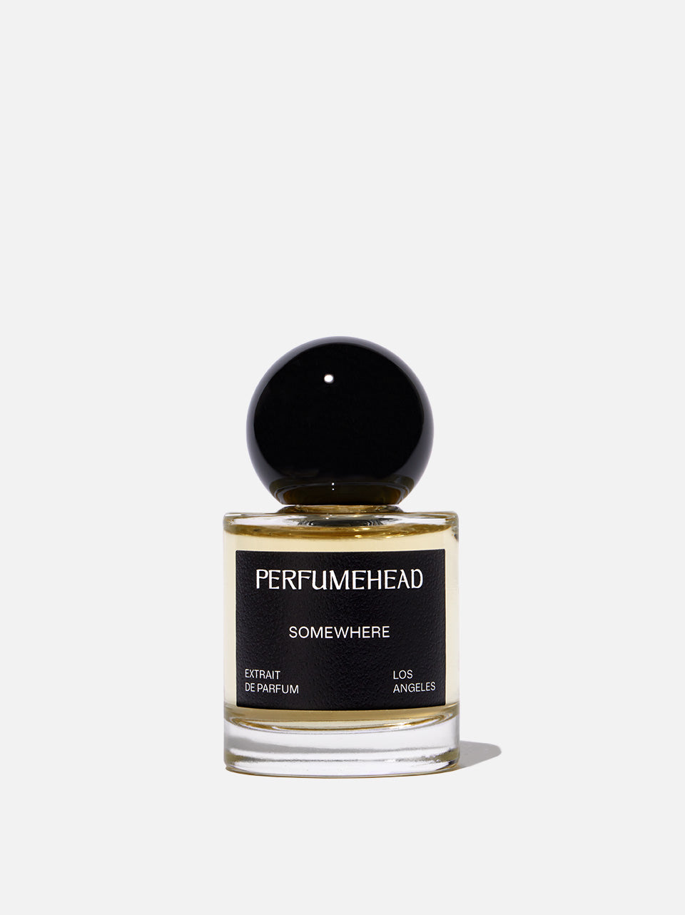 A bottle of Perfumehead 'SOMEWHERE' Eau de Parfum with a black spherical cap and a black label, set against a clean light gray background.