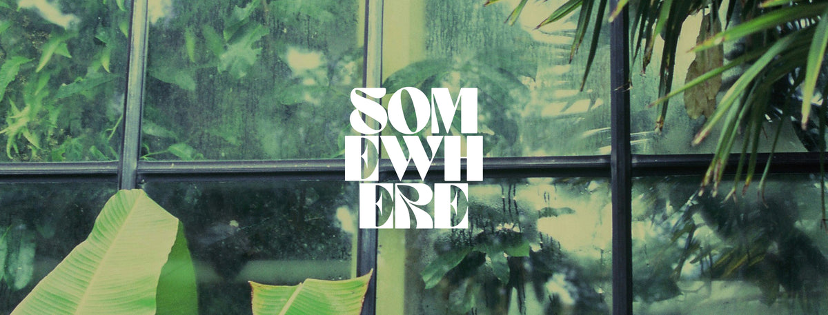 White stacked text reading 'SOMETHING' over a tropical greenhouse scene with glass panels, green foliage, and raindrops.