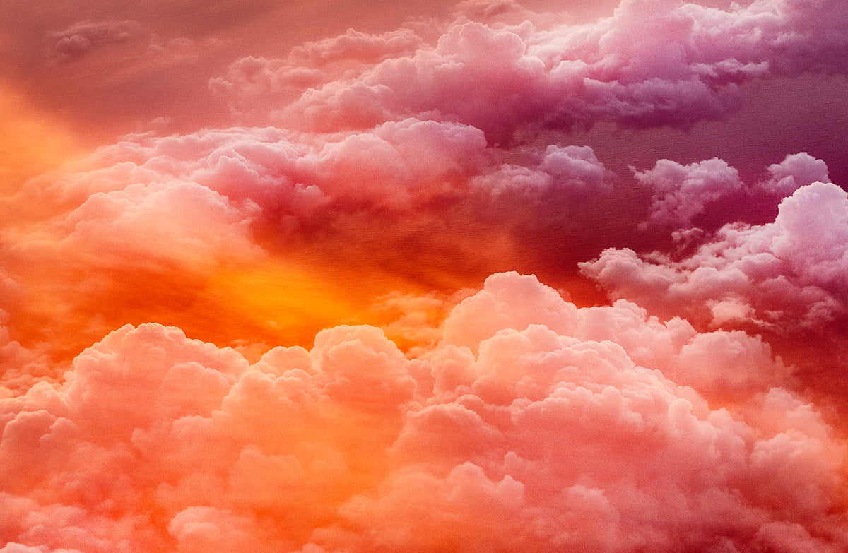 A dramatic sky filled with voluminous clouds in glowing shades of orange, pink, and purple, with sunlight breaking through the center.